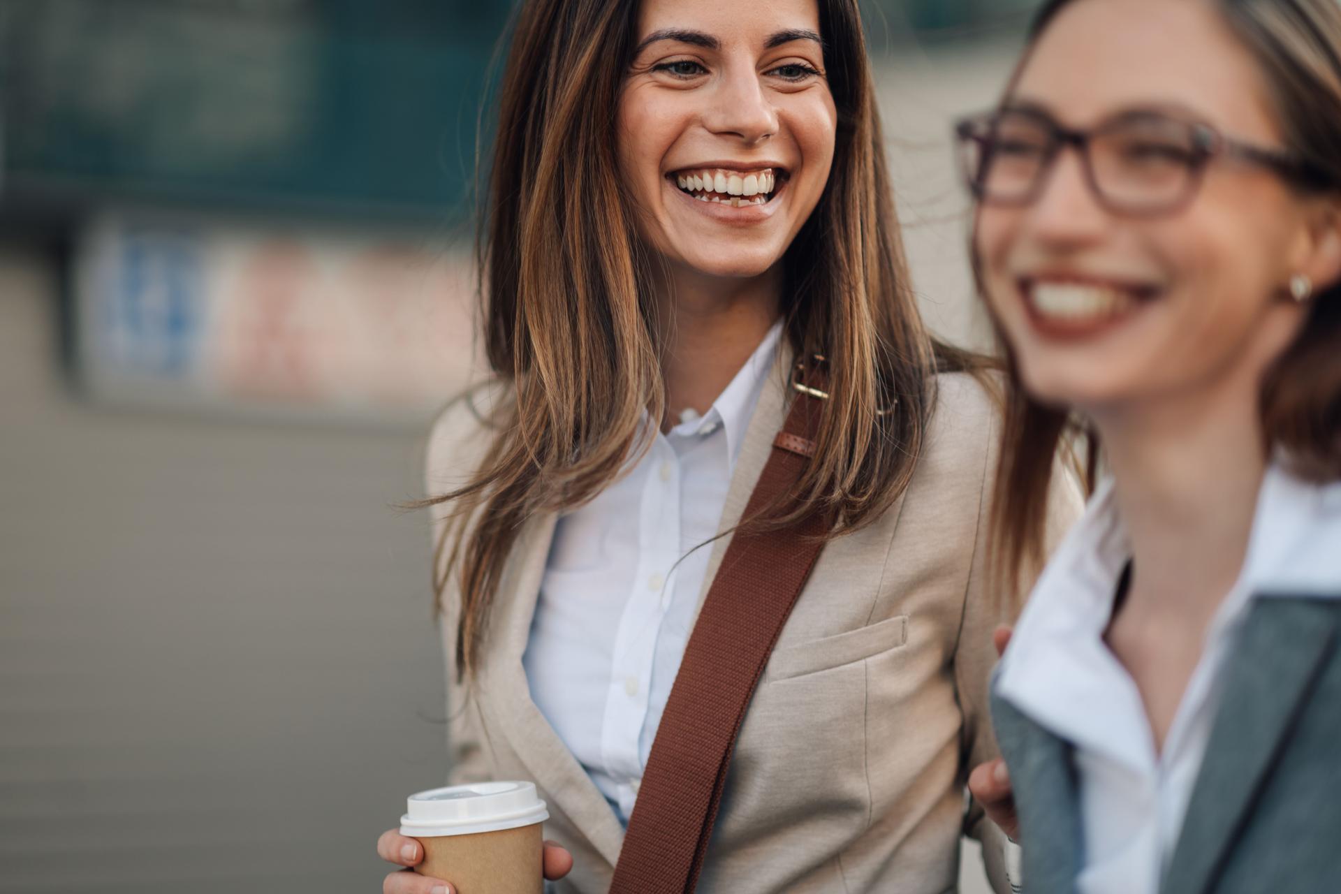 Two young businesswomen walking and talking during coffee break