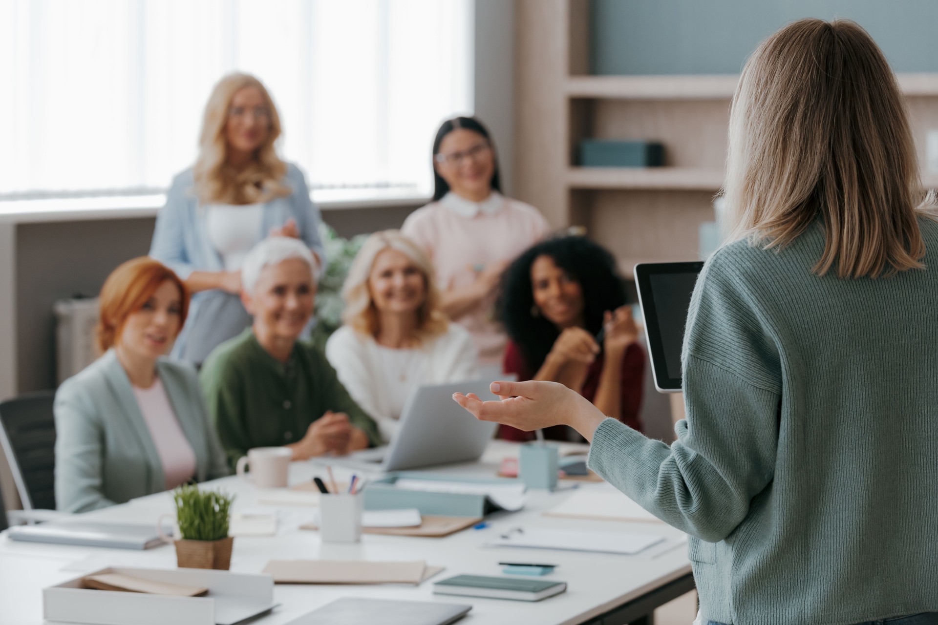 Group of mature women listening to speaker while having business training in office